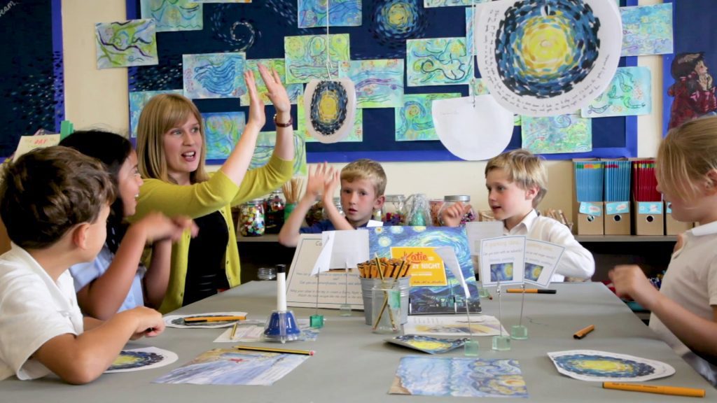 A teacher talking to children during an art lesson