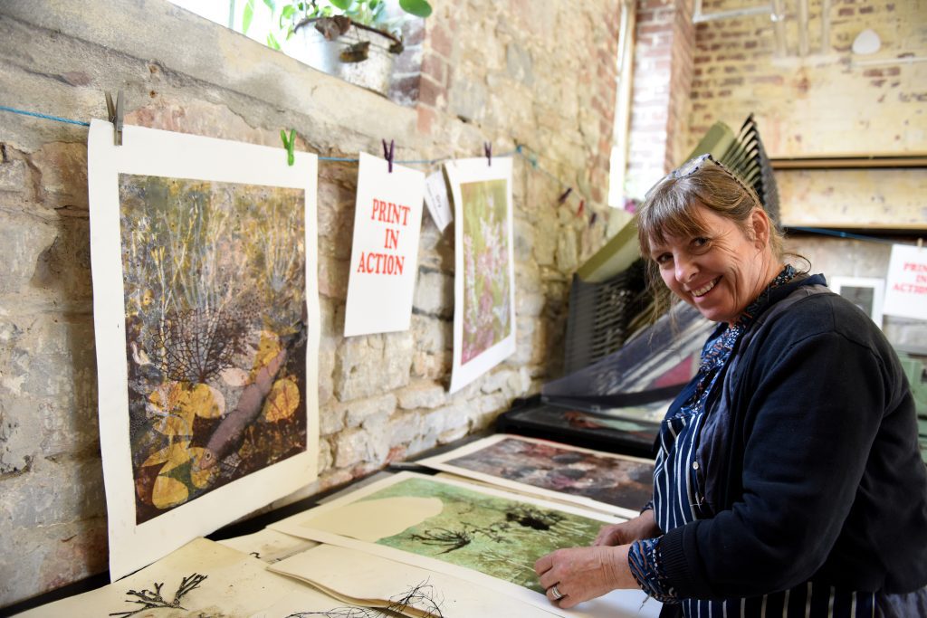 Print Artist in front of printed artwork in a creative co-work space