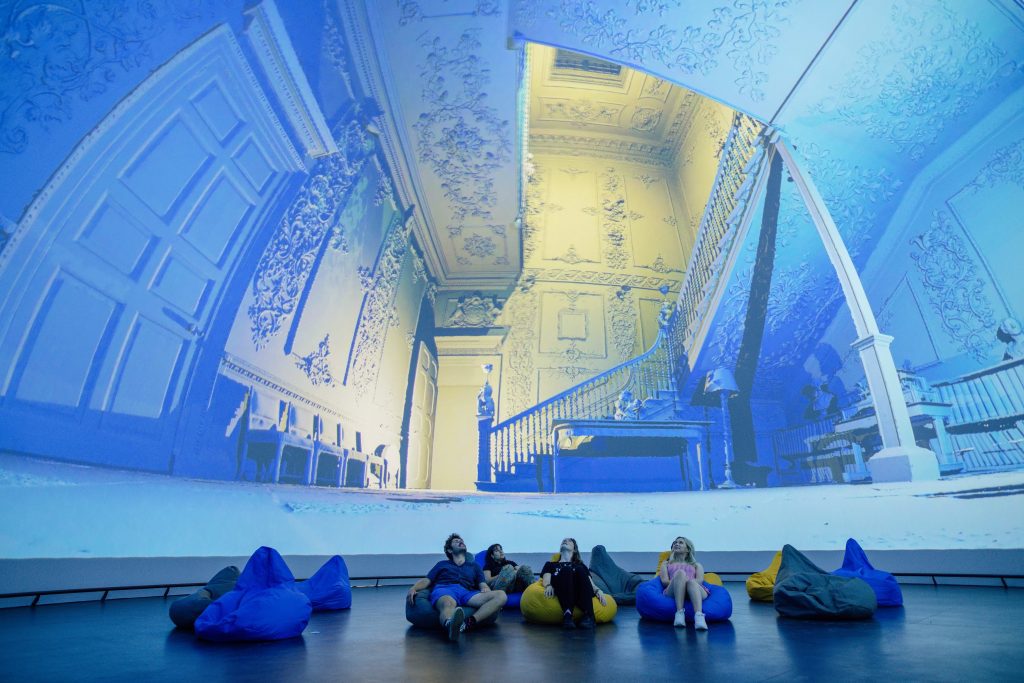 Group of people sat on bean bags watching an immersive dome experience